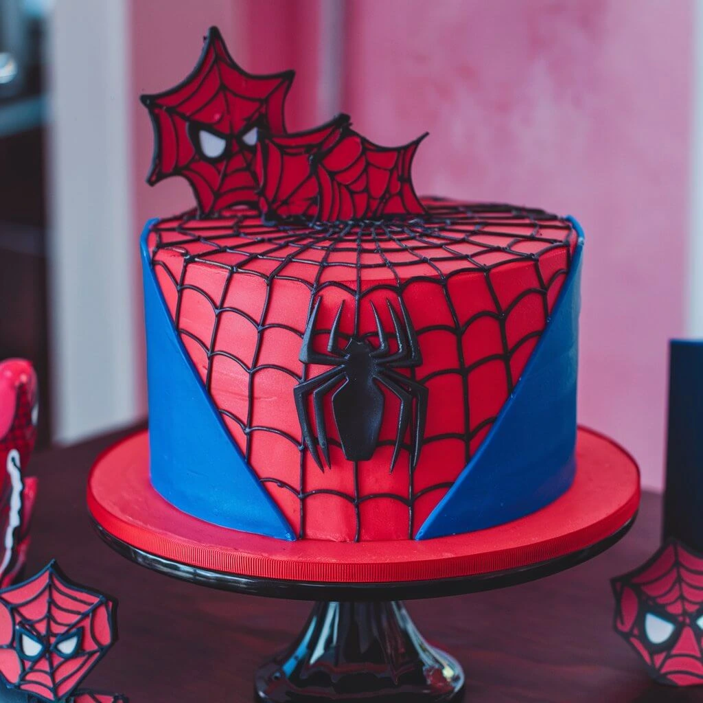 Spiderman cake featuring red and blue icing with a web design and Spiderman's face as a centerpiece.